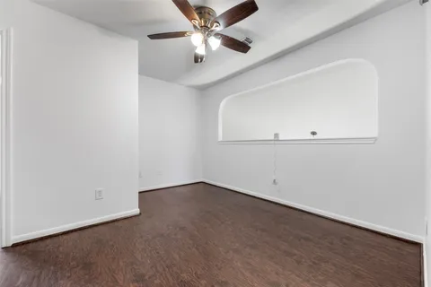 an empty room with wooden floor chandelier fan and windows