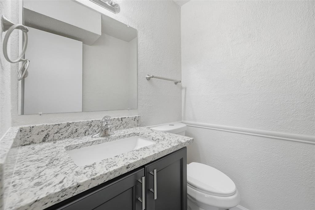 2702 Douglas Avenue, Unit 121 Dallas, TX 75219 - Photo 22 of 34 a bathroom with a granite countertop sink a toilet and a mirror