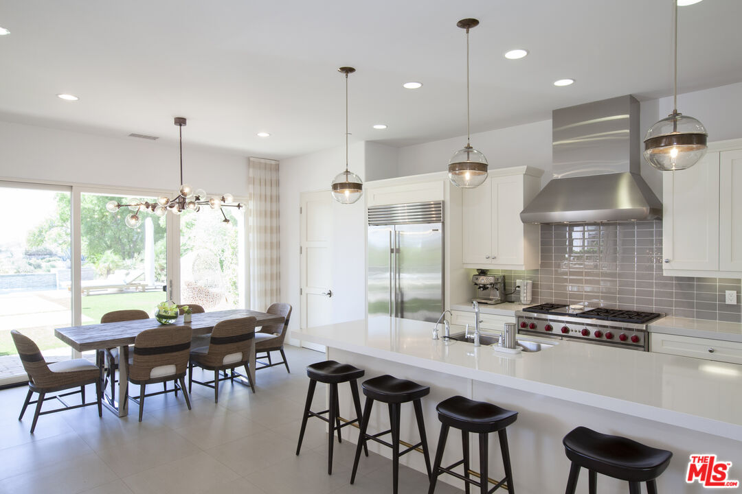 81805 Andalusia La Quinta, CA 92253 - Photo 12 of 45 a kitchen with stainless steel appliances granite countertop a stove a refrigerator a kitchen island a dining table and chairs