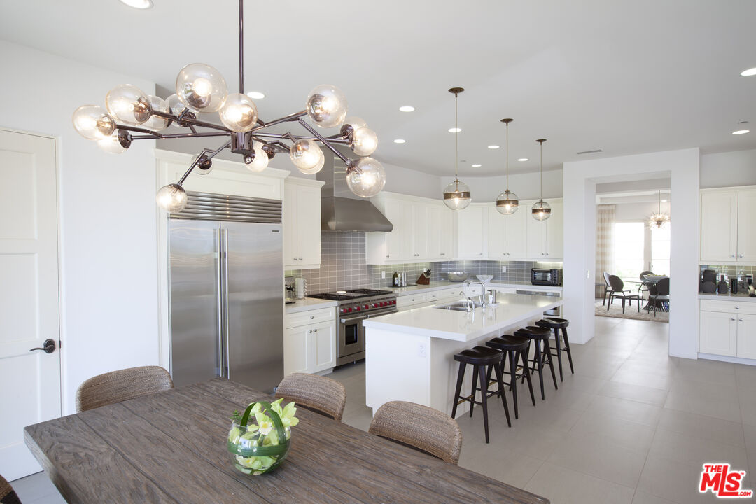 81805 Andalusia La Quinta, CA 92253 - Photo 15 of 45 a kitchen with stainless steel appliances kitchen island granite countertop a table chairs in it and view living room