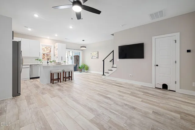 a view of a living room a dining room wooden floor and a ceiling fan