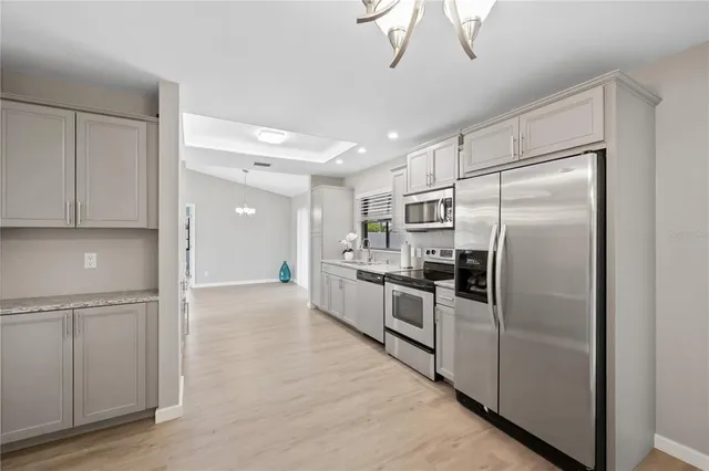 a large kitchen with a refrigerator a sink stainless steel appliances cabinets and a counter top space