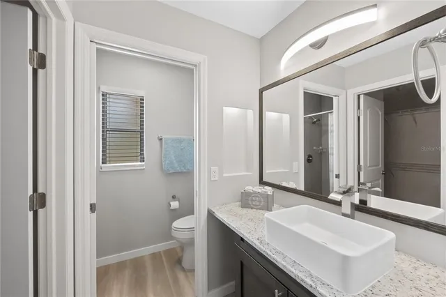 a bathroom with a granite countertop sink a toilet and a mirror