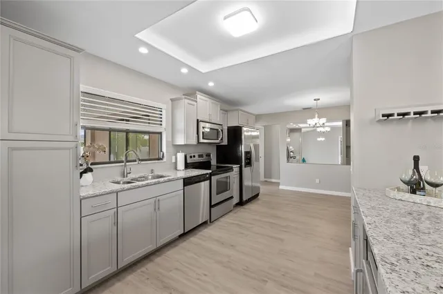 a large white kitchen with a sink and dishwasher a stove top oven with wooden floor