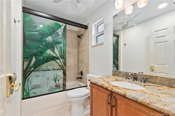 a bathroom with a granite countertop sink mirror vanity and toilet