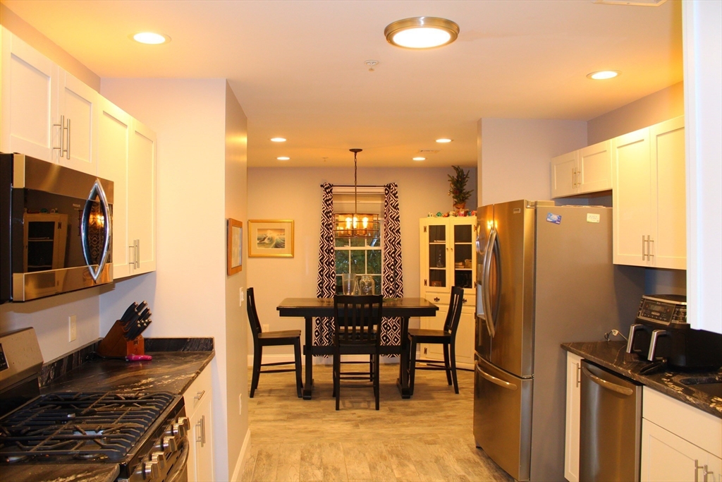 10 North Court Street, Unit 3 Fall River, MA 02720 - Photo 2 of 26 a kitchen with stainless steel appliances kitchen island granite countertop a table chairs and a refrigerator