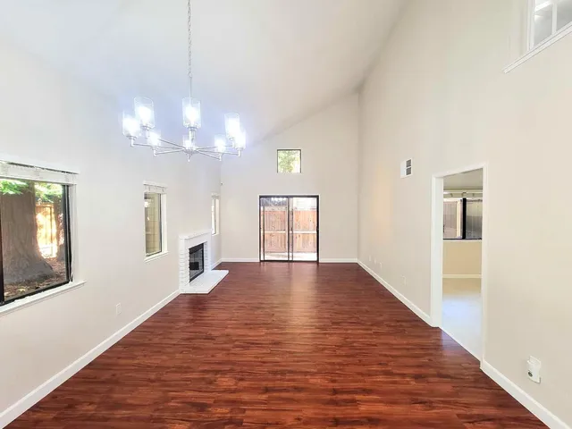 a view of an empty room with window and wooden floor