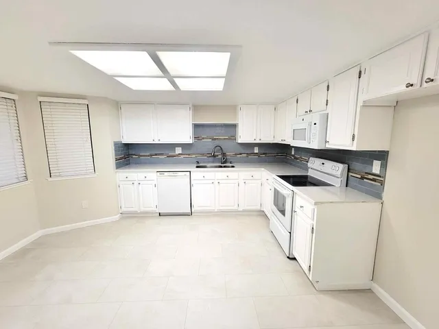 a kitchen with granite countertop white cabinets and white appliances
