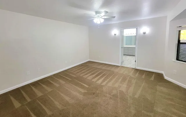 an empty room with windows and fan