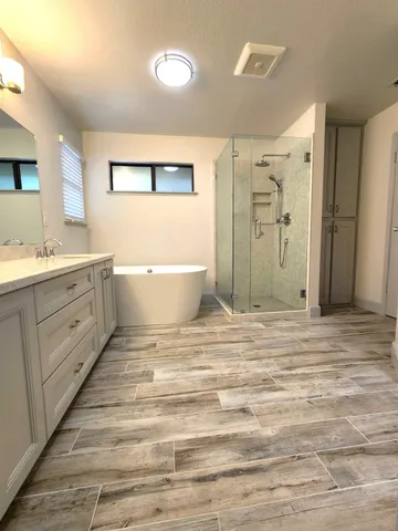 a spacious bathroom with a double vanity sink a large mirror and a bathtub