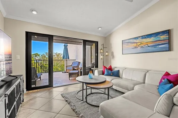 a living room with stainless steel appliances furniture a rug and a kitchen view