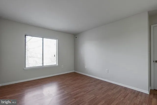 an empty room with wooden floor and window
