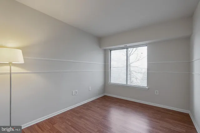 an empty room with wooden floor and window