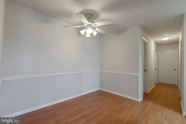 a view of a room with wooden floor closet ceiling fan and window