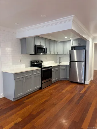 a kitchen with stainless steel appliances granite countertop a refrigerator a stove top oven a sink and dishwasher with wooden floor