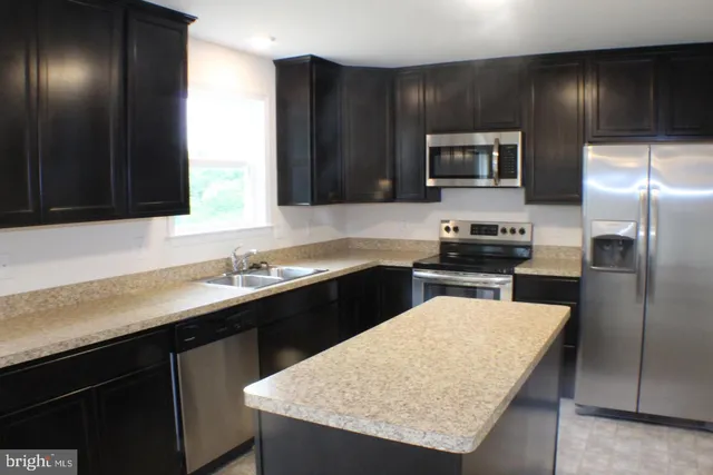 a kitchen with a sink dishwasher a refrigerator and a stove top oven