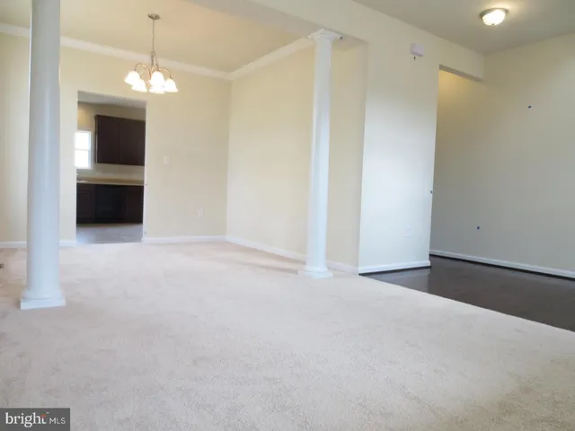 a view of an empty room with window and kitchen view