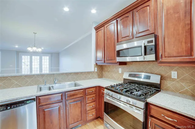 a kitchen with granite countertop wooden cabinets stainless steel appliances and a sink