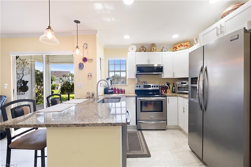 2008 Rookery Bay Drive, Unit 1102 Naples, FL 34114 - Photo 5 of 34 a kitchen with kitchen island a counter space a sink appliances and cabinets