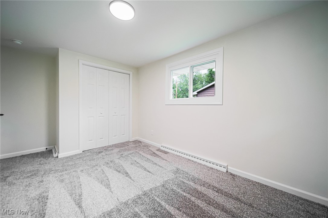 55 Elm Street Rittman, OH 44270 - Photo 24 of 46 Unfurnished bedroom featuring a baseboard radiator, baseboards, a closet, and carpet flooring