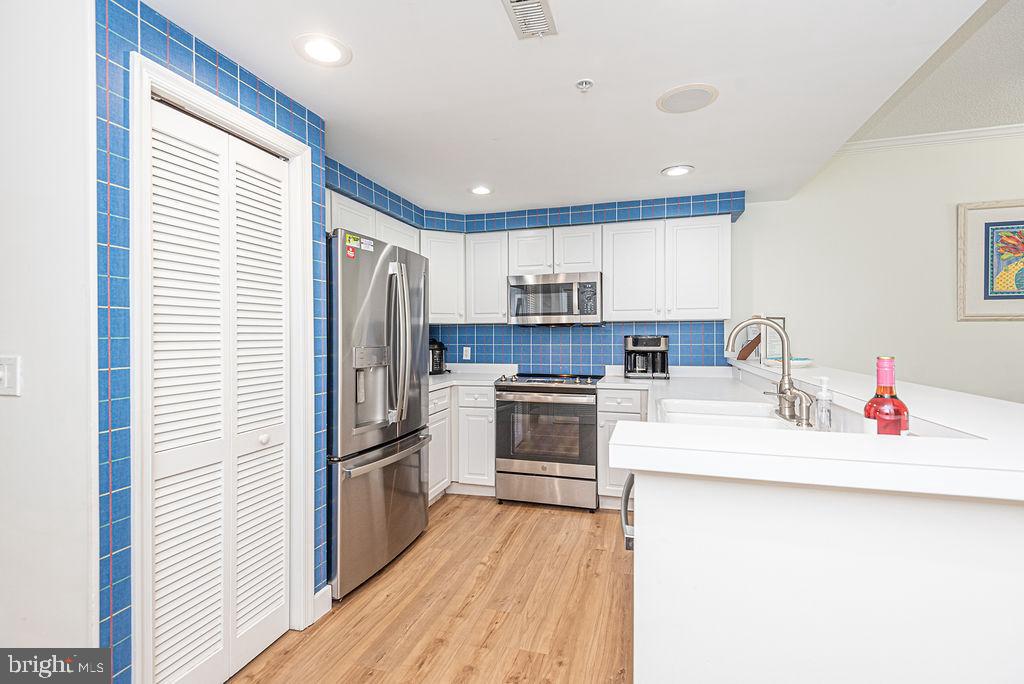 9 90th Street, Unit 102 Ocean City, MD 21842 - Photo 6 of 42 a kitchen with a refrigerator sink and wooden floor