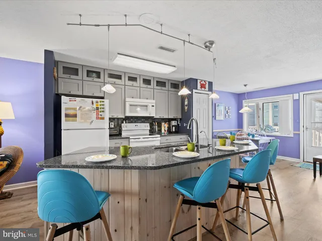 a kitchen with stainless steel appliances kitchen island granite countertop a table chairs in it and wooden floor