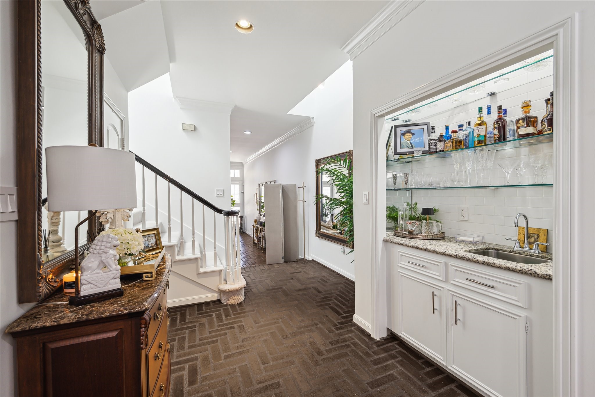 2220 Fulham Court Houston, TX 77063 - Photo 2 of 21 The wet bar, elegant brick floors, and sweeping stairway lead the eye into a light-filled living room that feels both refined and inviting.
