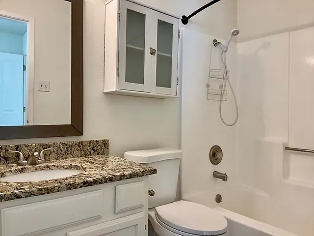 a bathroom with a granite countertop sink a toilet and shower