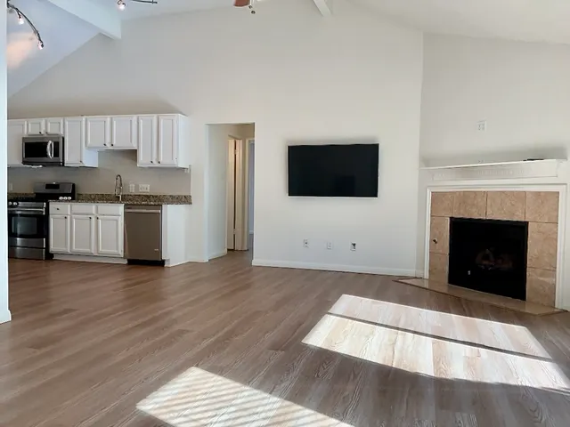 a living room with stainless steel appliances furniture a fireplace a flat screen tv and a fireplace