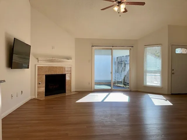 an empty room with windows fireplace and wooden floor