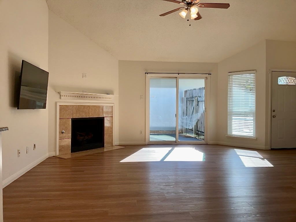 16912 Village Oak Loop Austin, TX 78717 - Photo 5 of 15 an empty room with windows fireplace and wooden floor