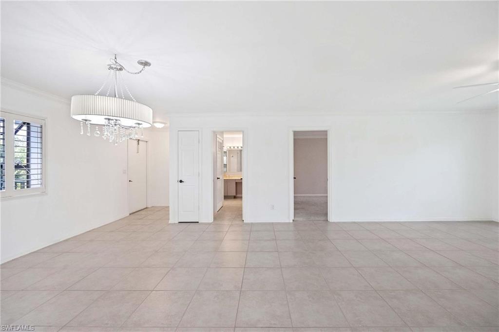1608 Spoonbill Lane, Unit B Naples, FL 34105 - Photo 6 of 31 an empty room with a chandelier fan and windows