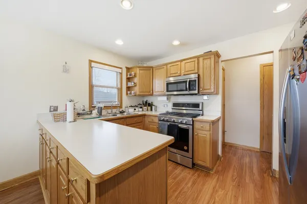 a kitchen with stainless steel appliances a stove a sink a refrigerator a center island and a window