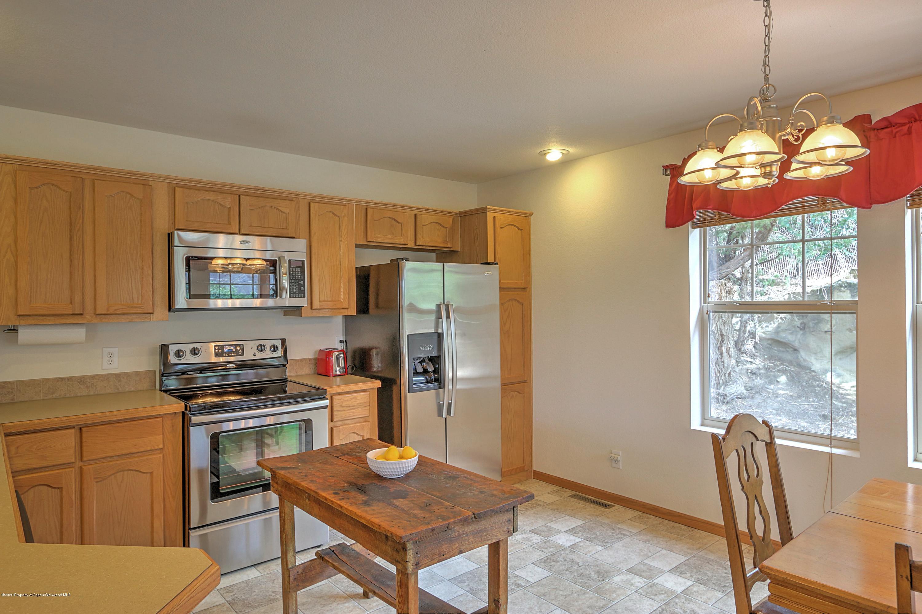 3045 Highway 325 Rifle, CO 81650 - Photo 7 of 35 a kitchen with a refrigerator a stove a sink dishwasher and a dining table with wooden floor