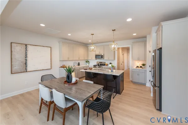 a kitchen with stainless steel appliances granite countertop a dining table chairs refrigerator and cabinets