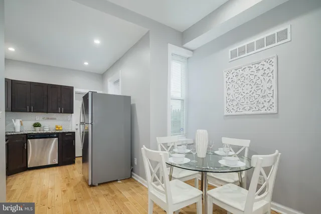 a kitchen with stainless steel appliances a refrigerator a sink a stove a dining table and chairs