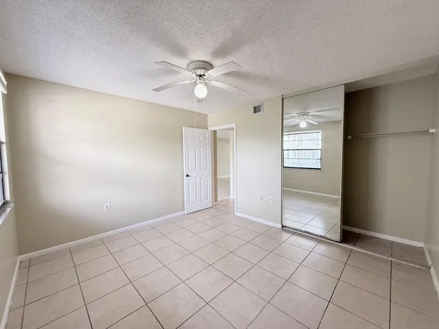 a view of an empty room and window with a kitchen