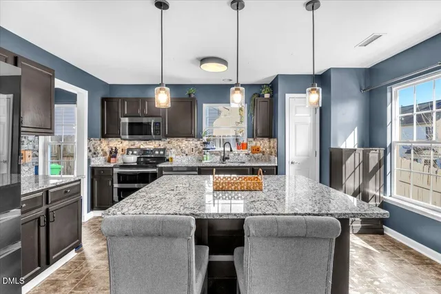 a kitchen with granite countertop a stove a sink a dining table and chairs
