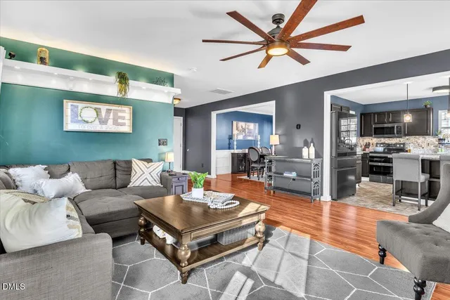 a living room with furniture a ceiling fan and a view of kitchen