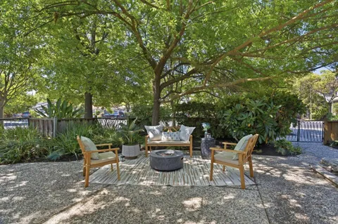 a view of a patio with table and chairs potted plants and large tree