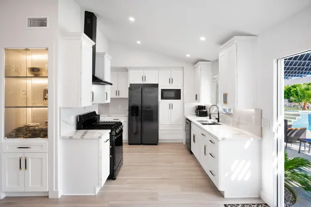a kitchen with stainless steel appliances kitchen island granite countertop a refrigerator a stove a sink dishwasher and a refrigerator with wooden floor