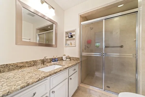 a bathroom with a granite countertop sink mirror and shower