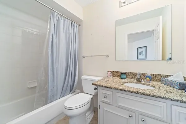 a bathroom with a granite countertop sink toilet and mirror