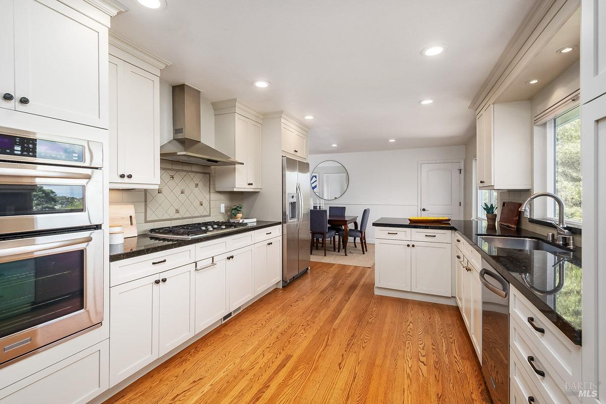 a large kitchen with stainless steel appliances and white cabinets