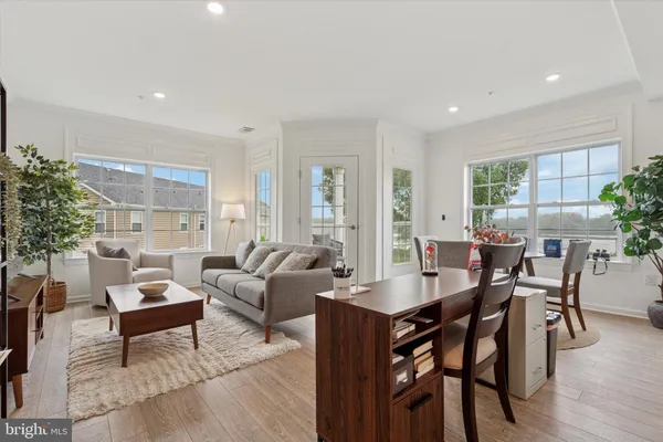 a living room with furniture a potted plant and open kitchen view