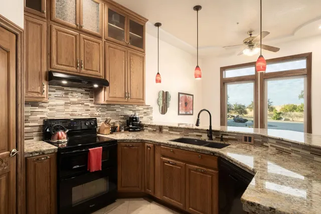a kitchen with granite countertop a sink a counter space appliances and cabinets