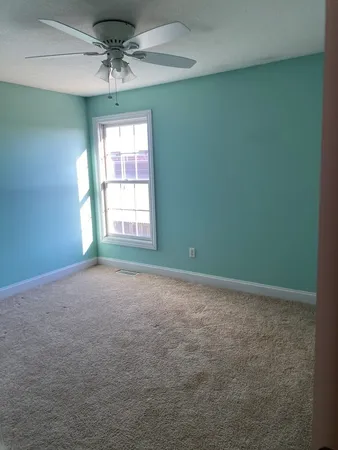 an empty room with a window and a fan