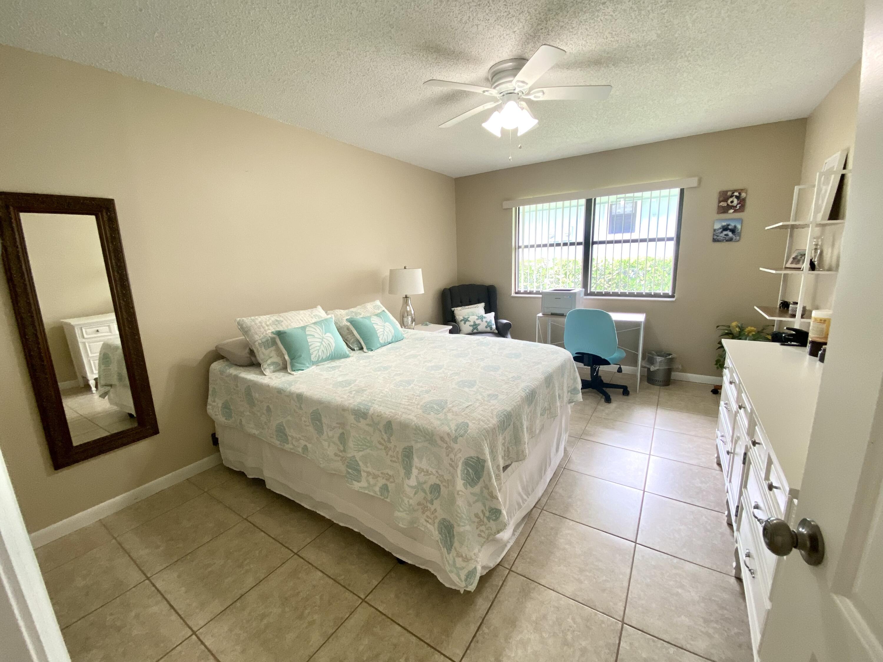 1127 East Seminole Avenue, Unit 13D Jupiter, FL 33477 - Photo 11 of 20 a bedroom with a bed and a chandelier