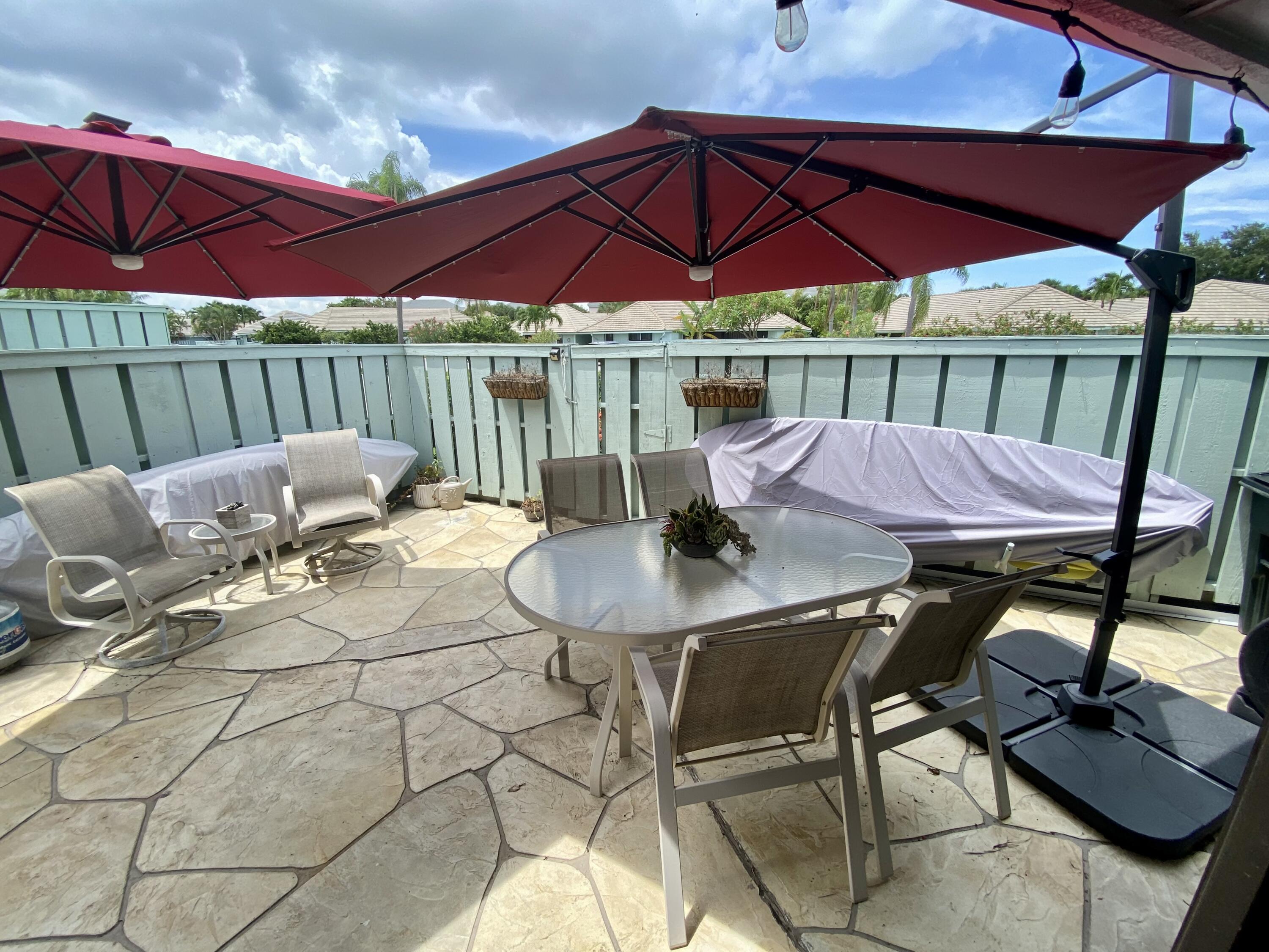 1127 East Seminole Avenue, Unit 13D Jupiter, FL 33477 - Photo 14 of 20 a patio with a patio table and chairs under an umbrella