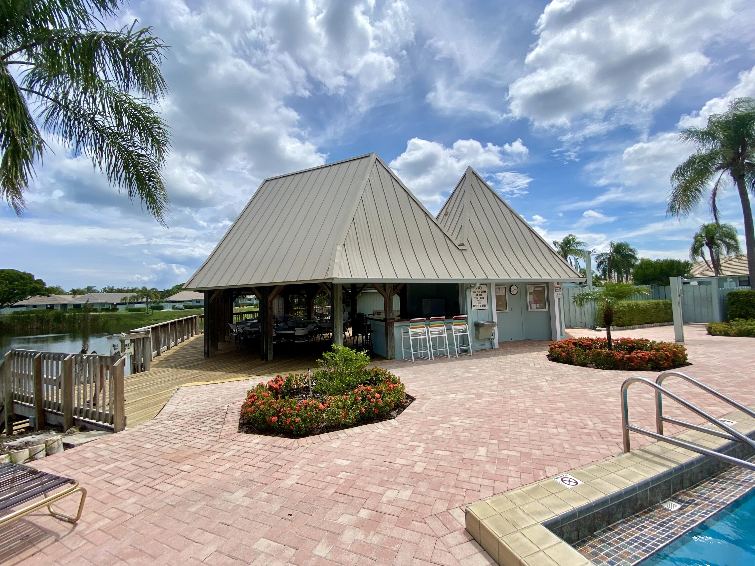 1127 East Seminole Avenue, Unit 13D Jupiter, FL 33477 - Photo 18 of 20 a front view of a house with garden and patio